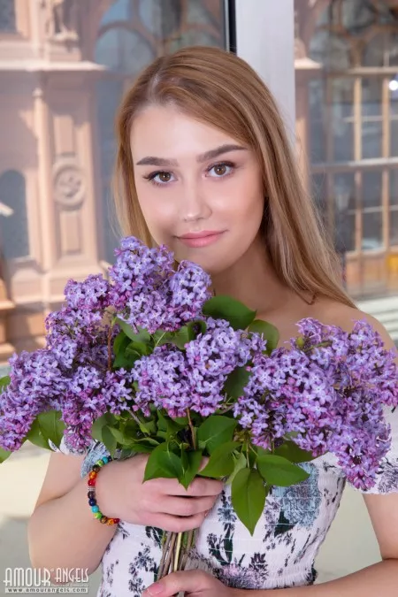 Young blonde Tabi holds fresh picked flowers while getting butt naked