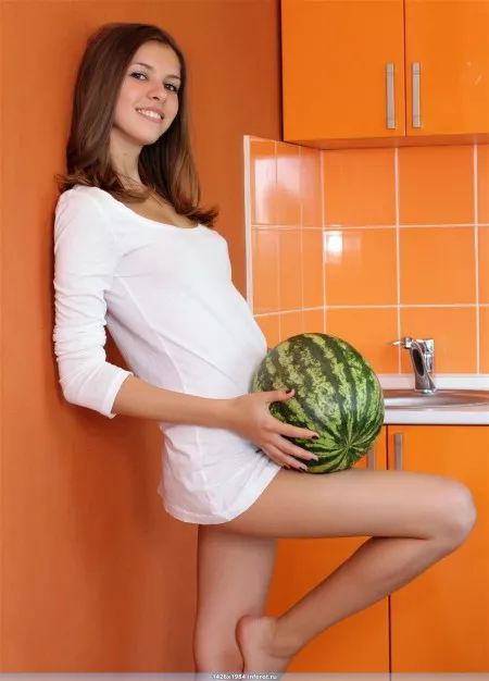 Beautiful naked girl in the kitchen with watermelon