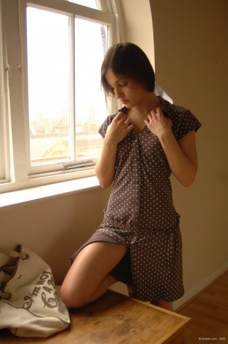 Solo girl slips off her dress and underthings in front of a window