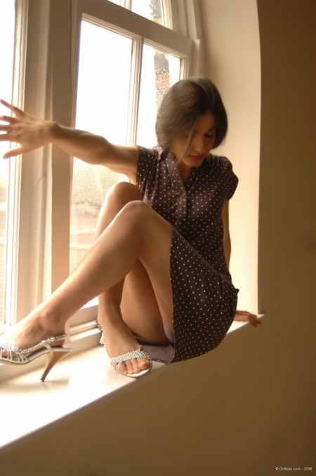 Solo girl slips off her dress and underthings in front of a window